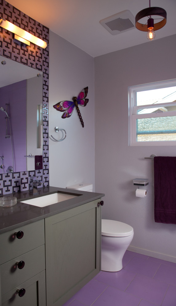 Exemple d'une petite salle d'eau rétro avec un placard à porte shaker, des portes de placard grises, une baignoire en alcôve, une douche ouverte, WC à poser, un carrelage rose, des carreaux de céramique, un mur violet, un sol en carrelage de porcelaine, un lavabo de ferme, un plan de toilette en quartz modifié, un sol violet, une cabine de douche à porte coulissante, un plan de toilette gris, des toilettes cachées, meuble simple vasque et meuble-lavabo suspendu.