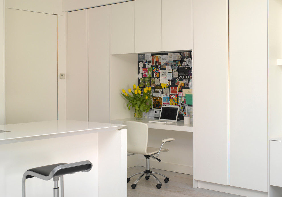 This is an example of a large contemporary kitchen in London with flat-panel cabinets, white cabinets, quartz benchtops and an undermount sink.