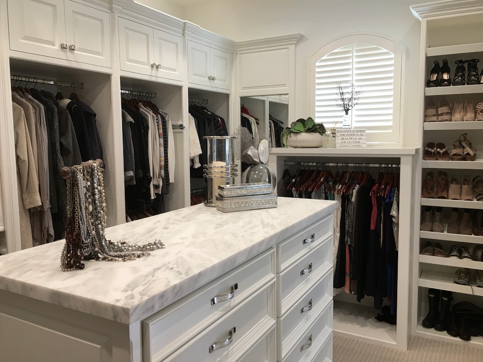 Inspiration for a large beach style gender-neutral walk-in wardrobe in Orange County with raised-panel cabinets, white cabinets, carpet and beige floor.
