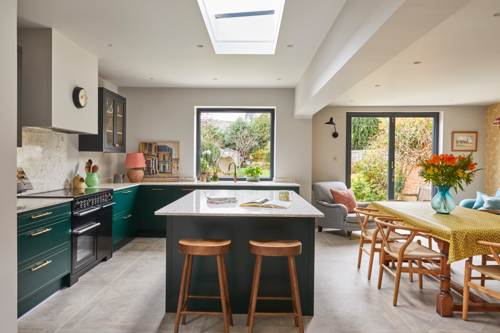 Stilmix Wohnküche in L-Form mit Unterbauwaschbecken, flächenbündigen Schrankfronten, grünen Schränken, schwarzen Elektrogeräten, Kücheninsel, grauem Boden und weißer Arbeitsplatte in Gloucestershire