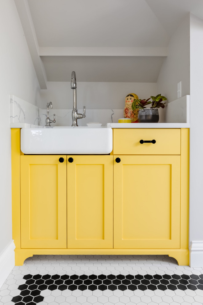 Design ideas for a mid-sized arts and crafts u-shaped dedicated laundry room in Seattle with a farmhouse sink, shaker cabinets, yellow cabinets, quartz benchtops, engineered quartz splashback, grey walls, white benchtop and vaulted.