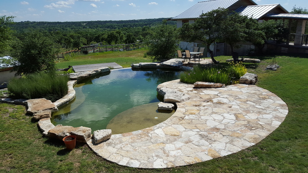 Photo of a mediterranean front yard custom-shaped natural pool in Austin with a water feature.