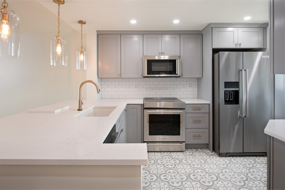 This is an example of a small grey and white l-shaped kitchen in Miami with a submerged sink, shaker cabinets, grey cabinets, quartz worktops, white splashback, ceramic splashback, stainless steel appliances, a breakfast bar, green floors and white worktops.