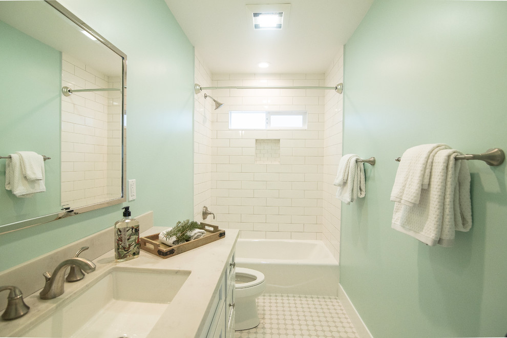 This is an example of a mid-sized transitional 3/4 bathroom in Los Angeles with recessed-panel cabinets, white cabinets, an alcove tub, a shower/bathtub combo, a two-piece toilet, white tile, subway tile, green walls, ceramic floors, an undermount sink, marble benchtops, white floor, a shower curtain and white benchtops.