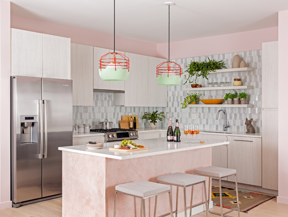 This is an example of a mid-sized eclectic l-shaped eat-in kitchen in Boston with an undermount sink, flat-panel cabinets, light wood cabinets, grey splashback, stainless steel appliances, with island, white benchtop and medium hardwood floors.