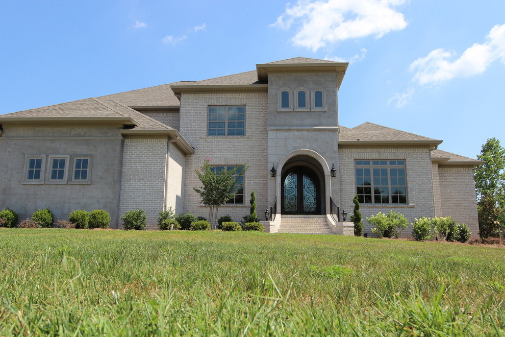 Large mediterranean two-storey brick beige house exterior in Nashville with a gable roof and a shingle roof.