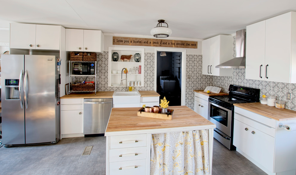 Mid-sized country l-shaped open plan kitchen in Raleigh with a farmhouse sink, flat-panel cabinets, white cabinets, wood benchtops, grey splashback, porcelain splashback, stainless steel appliances, vinyl floors and with island.