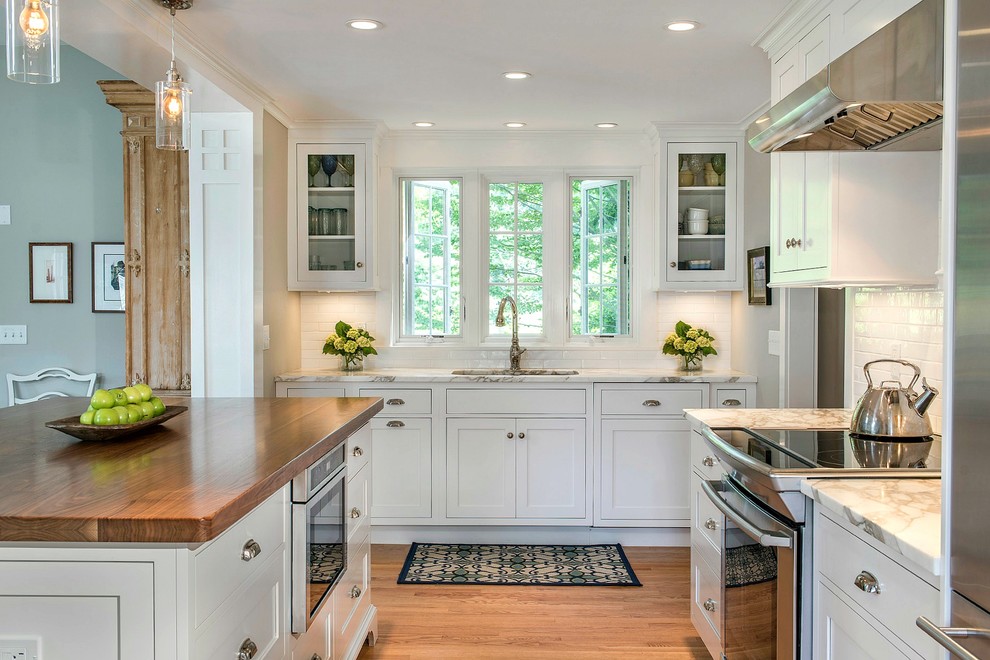 Design ideas for a mid-sized country l-shaped eat-in kitchen in Other with an undermount sink, white cabinets, wood benchtops, white splashback, stainless steel appliances, with island, shaker cabinets, subway tile splashback, medium hardwood floors and brown floor.