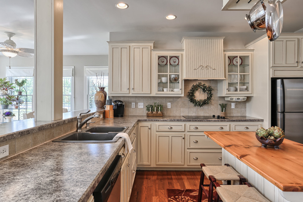 Inspiration for a traditional l-shaped open plan kitchen in Orange County with a double-bowl sink, shaker cabinets, beige cabinets, laminate benchtops, beige splashback, porcelain splashback, stainless steel appliances, medium hardwood floors and with island.