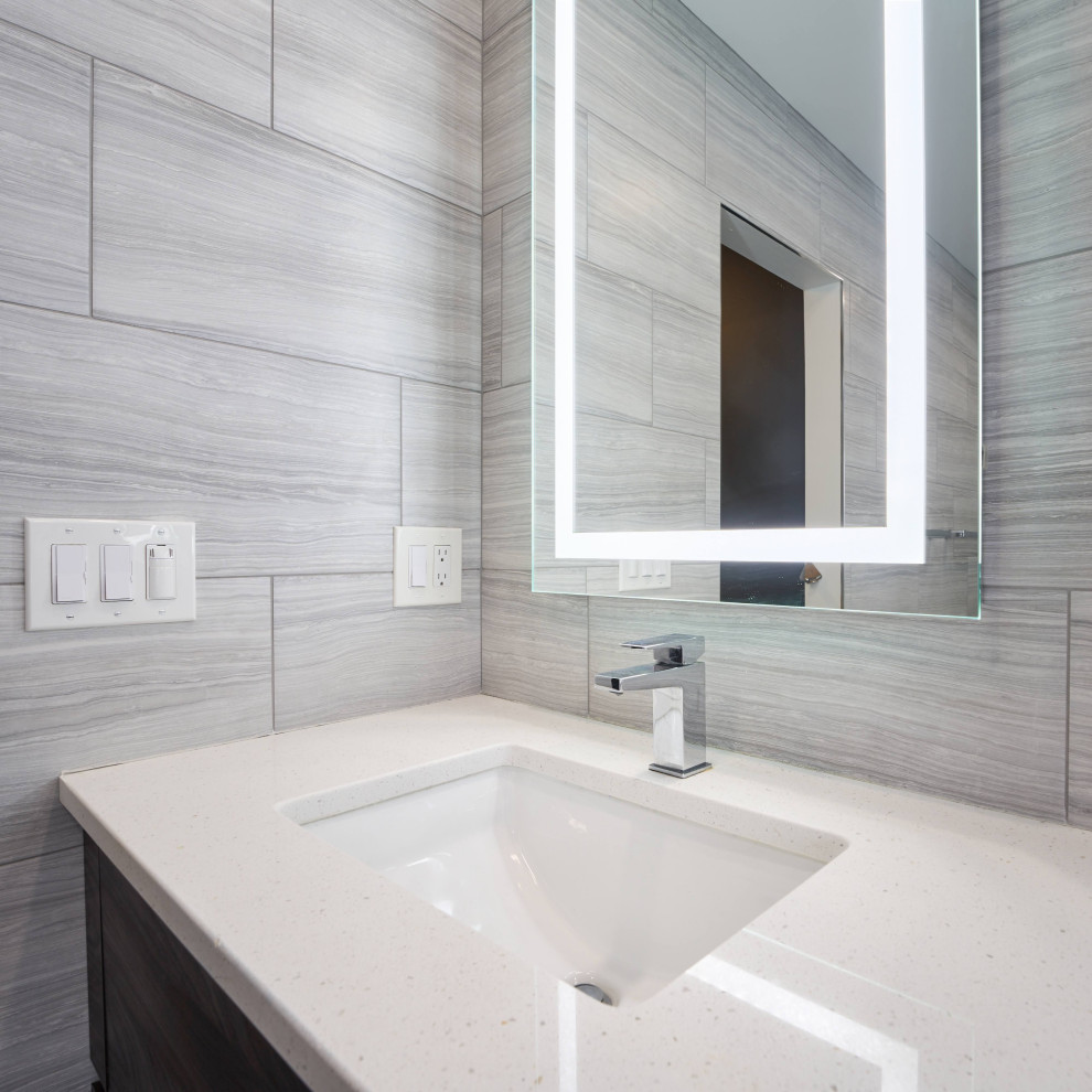 Mid-sized modern master bathroom in Philadelphia with flat-panel cabinets, gray tile, grey walls, grey floor, a hinged shower door, white benchtops, a shower seat, a double vanity, grey cabinets, a two-piece toilet, ceramic tile, linoleum floors, a drop-in sink, limestone benchtops and a built-in vanity.