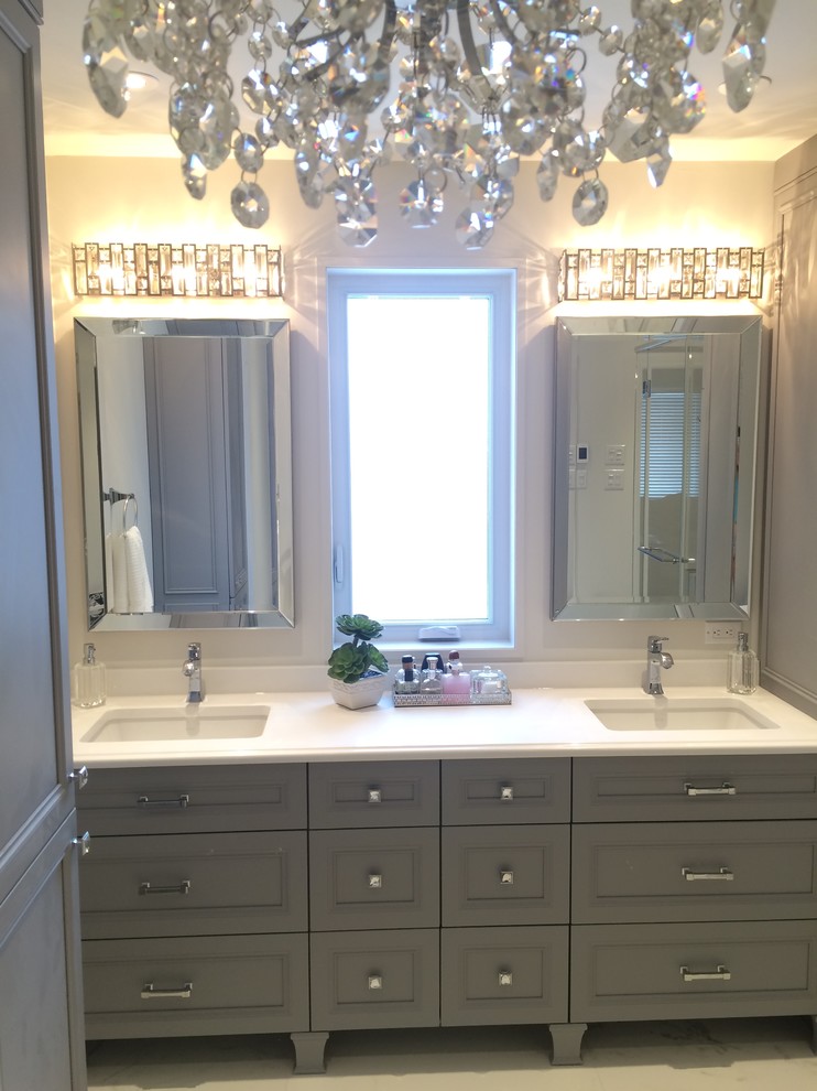 This is an example of a large transitional master bathroom in Montreal with furniture-like cabinets, grey cabinets, a freestanding tub, a curbless shower, a one-piece toilet, white tile, porcelain tile, grey walls, porcelain floors, an undermount sink and engineered quartz benchtops.