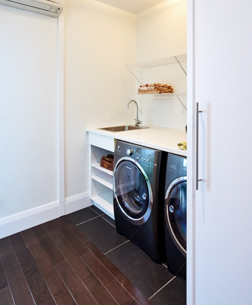 This is an example of a small contemporary single-wall laundry cupboard in Toronto with a single-bowl sink, open cabinets, white cabinets, laminate benchtops, white walls, porcelain floors and a side-by-side washer and dryer.