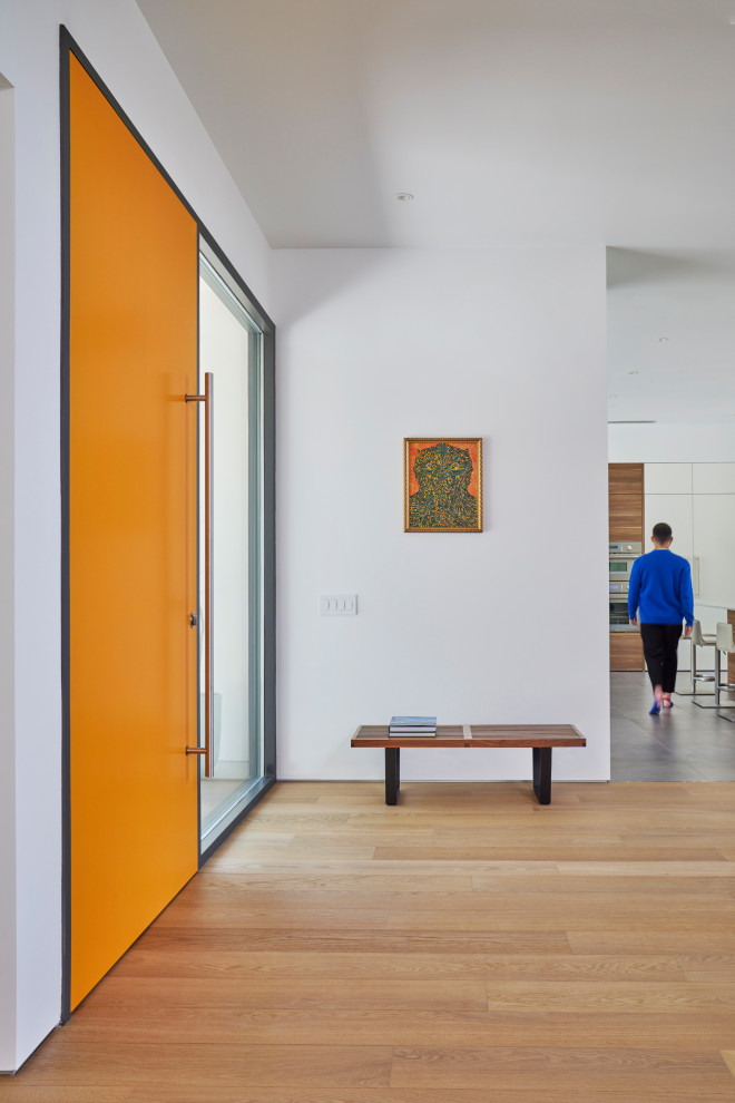 Large modern foyer in Los Angeles with white walls, medium hardwood floors, a single front door, an orange front door and brown floor.