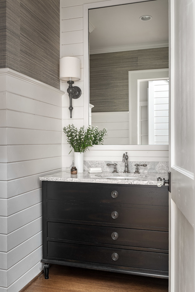 Design ideas for a mid-sized beach style powder room in Atlanta with engineered quartz benchtops, furniture-like cabinets, brown cabinets, multi-coloured walls, medium hardwood floors, an undermount sink and grey benchtops.