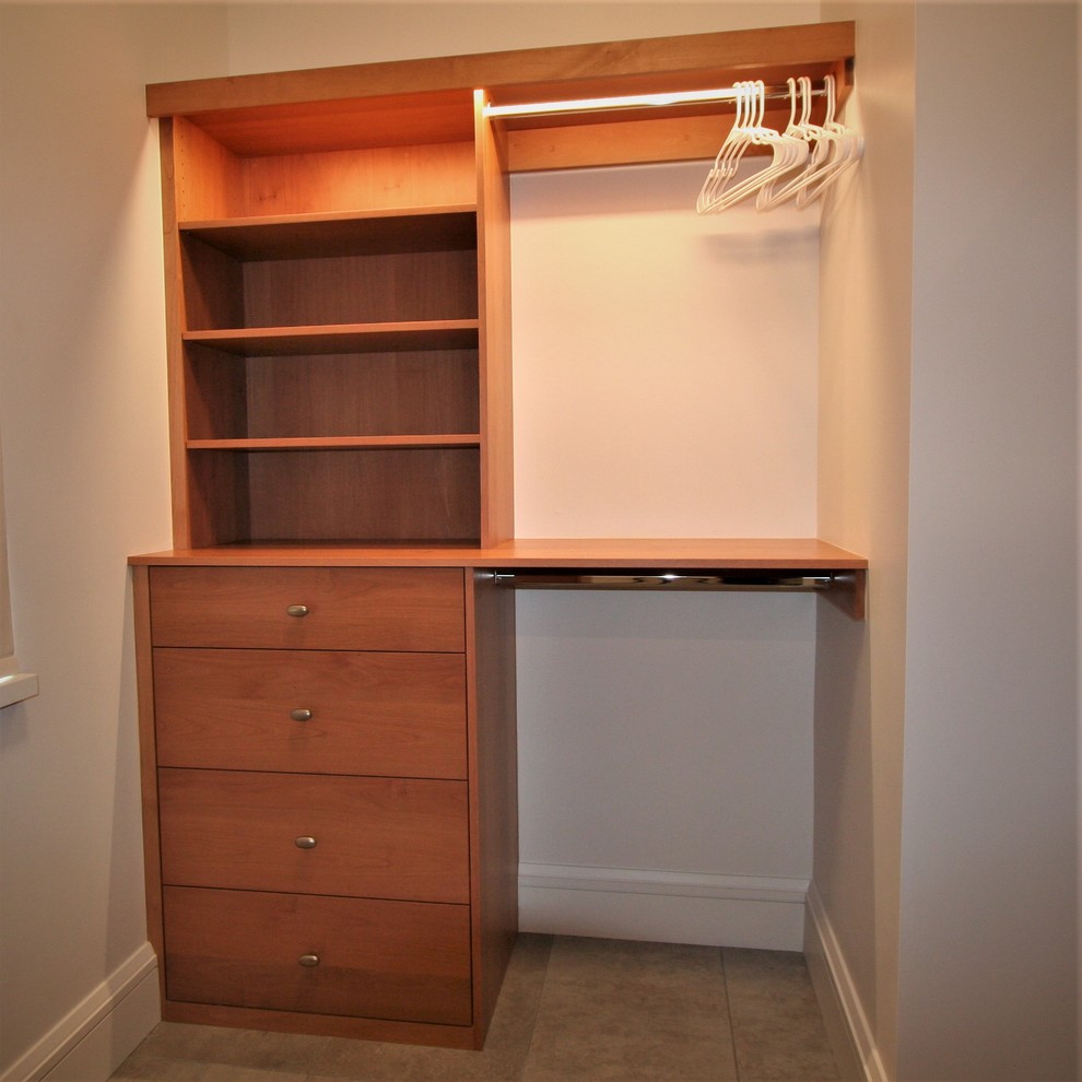 Small traditional gender-neutral walk-in wardrobe in Other with flat-panel cabinets, medium wood cabinets, ceramic floors and beige floor.