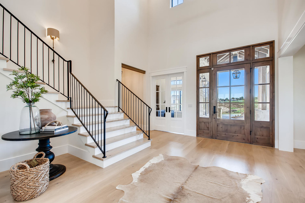 Large country foyer in Denver with white walls, light hardwood floors and a single front door.