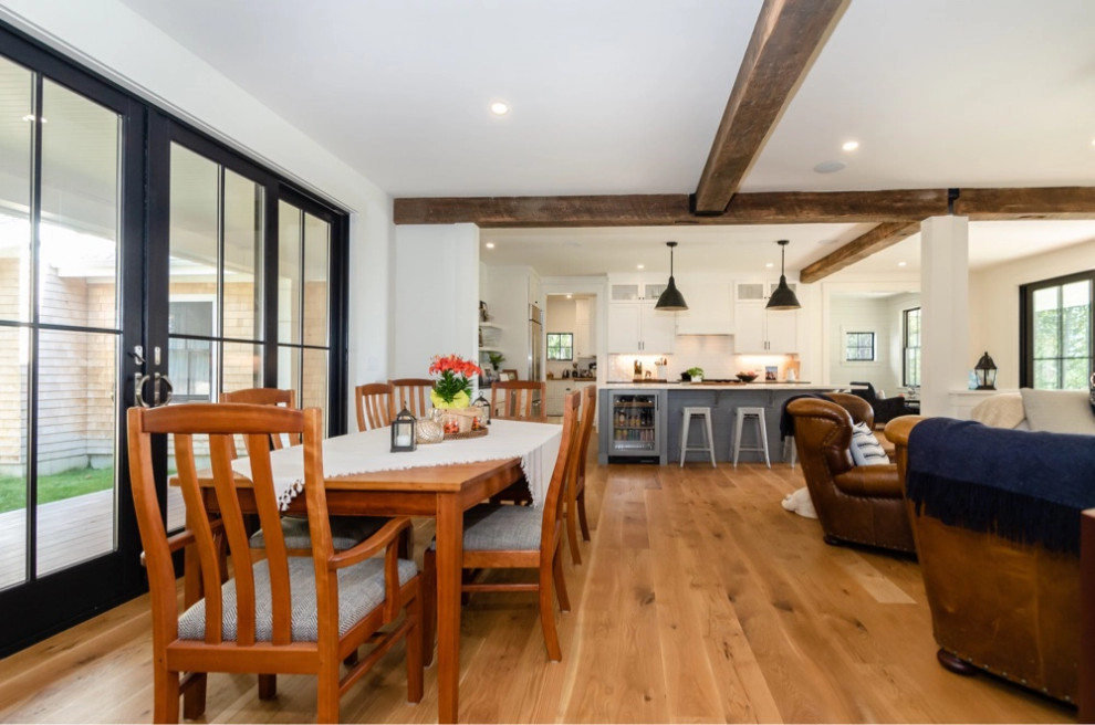 Exemple d'une salle à manger ouverte sur la cuisine bord de mer avec un sol en bois brun, un sol marron et poutres apparentes.