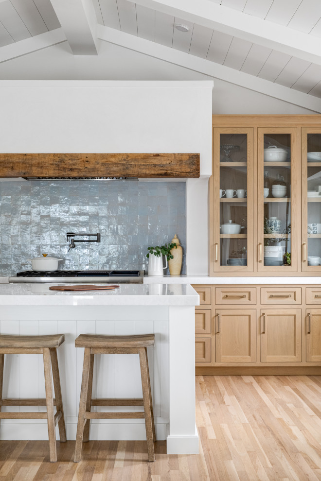 This is an example of a small beach style single-wall open plan kitchen in Orange County with shaker cabinets, light wood cabinets, quartz benchtops, blue splashback, terra-cotta splashback, panelled appliances, with island, white benchtop and vaulted.