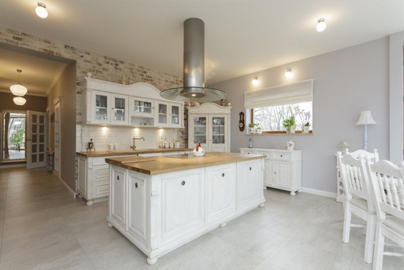 Mid-sized country galley eat-in kitchen in Atlanta with a drop-in sink, glass-front cabinets, white cabinets, wood benchtops, white splashback, porcelain splashback, porcelain floors, with island and grey floor.