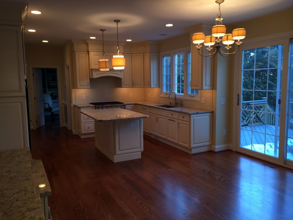 Mountain style l-shaped medium tone wood floor eat-in kitchen photo in DC Metro with an undermount sink, raised-panel cabinets, white cabinets, marble countertops, white backsplash, stone slab backsplash, stainless steel appliances and an island