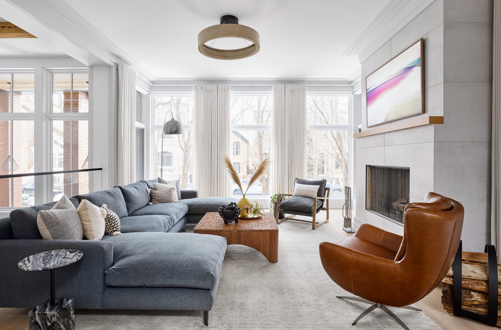 Ejemplo de salón para visitas tipo loft contemporáneo con paredes blancas, suelo de madera clara, todas las chimeneas, marco de chimenea de baldosas y/o azulejos y televisor retractable