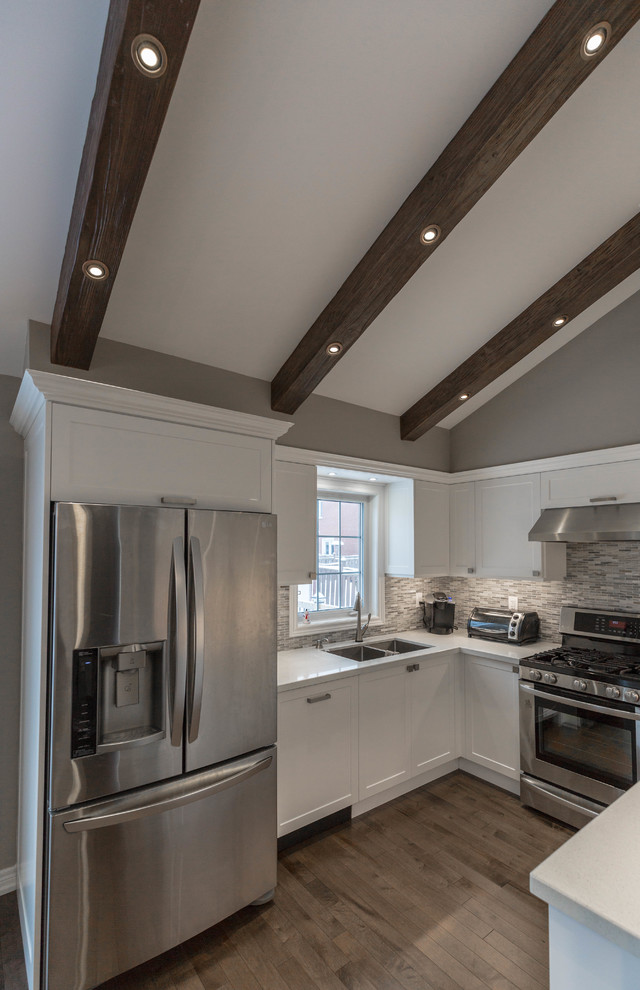 Example of a mid-sized transitional u-shaped medium tone wood floor and brown floor open concept kitchen design in Toronto with a double-bowl sink, recessed-panel cabinets, white cabinets, quartz countertops, gray backsplash, marble backsplash, stainless steel appliances, no island and white countertops