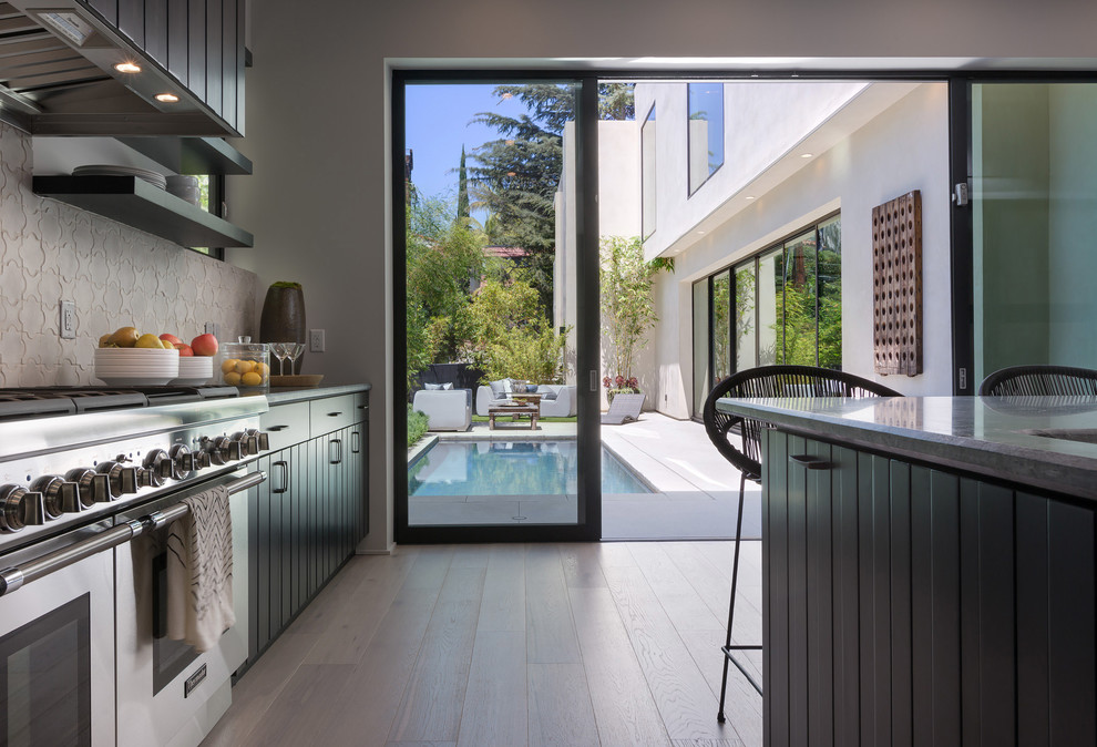 This is an example of a large contemporary l-shaped open plan kitchen in Los Angeles with a farmhouse sink, beaded inset cabinets, dark wood cabinets, marble benchtops, beige splashback, ceramic splashback, stainless steel appliances, porcelain floors, with island, beige floor and grey benchtop.