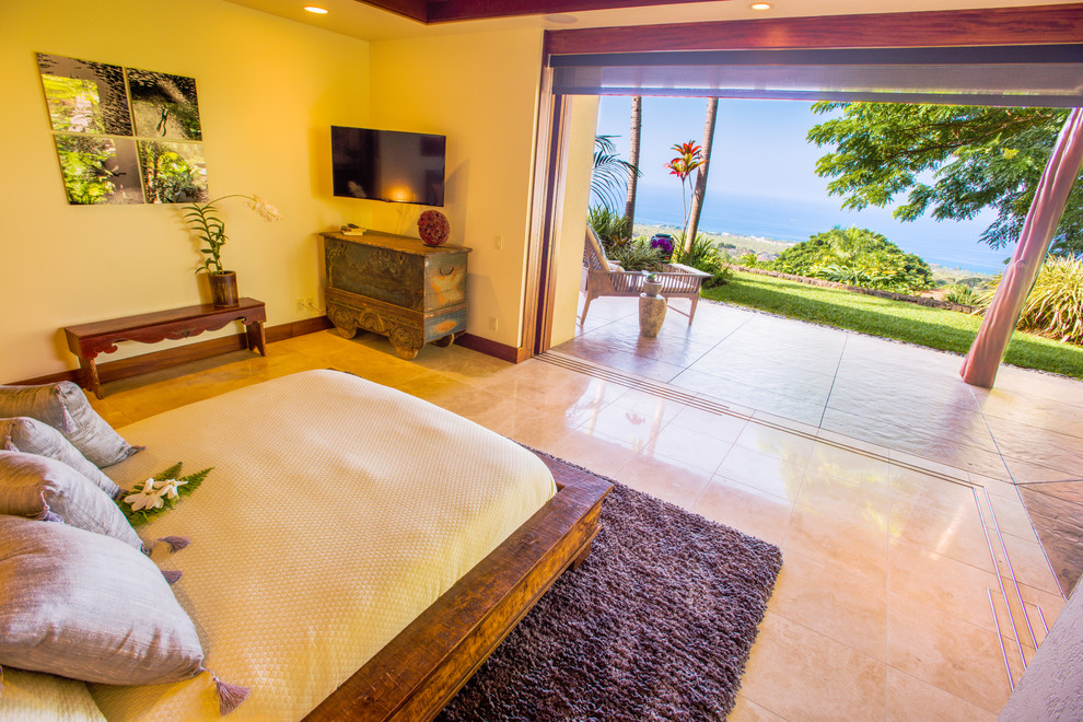 Design ideas for a mid-sized tropical master bedroom in Hawaii with beige walls and limestone floors.