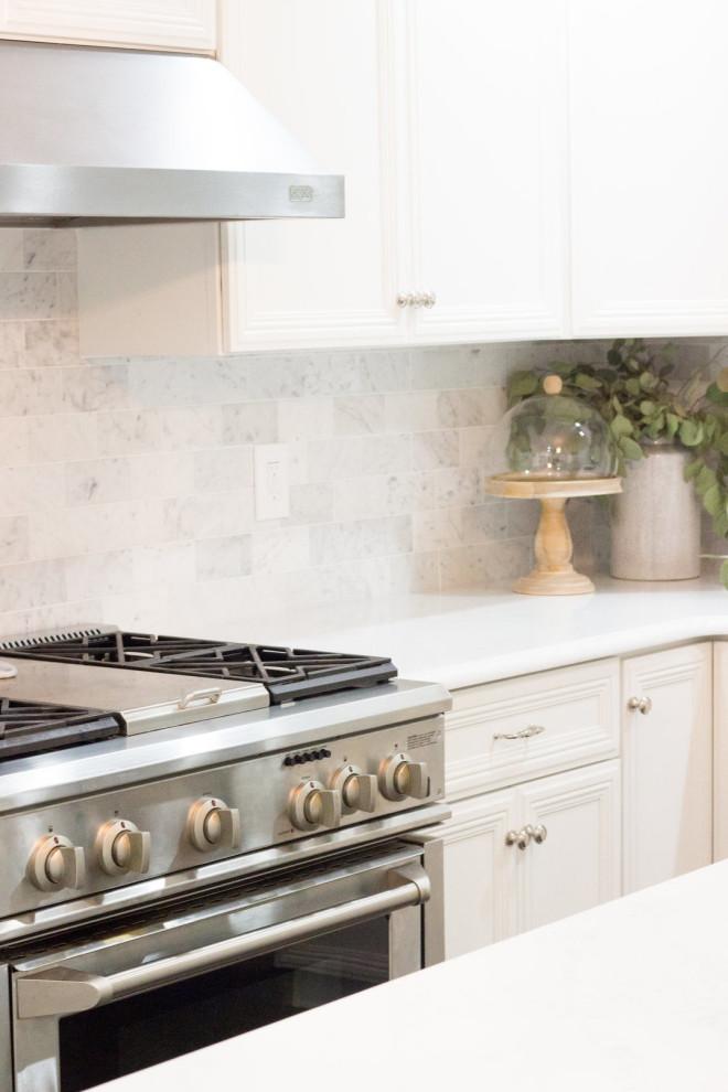 Kitchen photo in Los Angeles with a drop-in sink, quartz countertops, white backsplash, stainless steel appliances, an island and white countertops