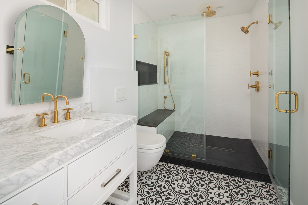 Design ideas for a large transitional master bathroom in Los Angeles with furniture-like cabinets, white cabinets, an alcove shower, a wall-mount toilet, white tile, porcelain tile, white walls, cement tiles, an undermount sink, marble benchtops, black floor, a hinged shower door and white benchtops.