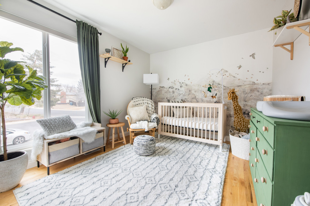 Immagine di una piccola cameretta per neonati neutra boho chic con pareti beige, parquet chiaro e carta da parati