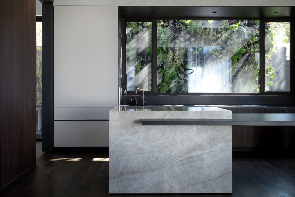 This is an example of an expansive contemporary single-wall kitchen in Melbourne with marble benchtops, black splashback, dark hardwood floors and with island.