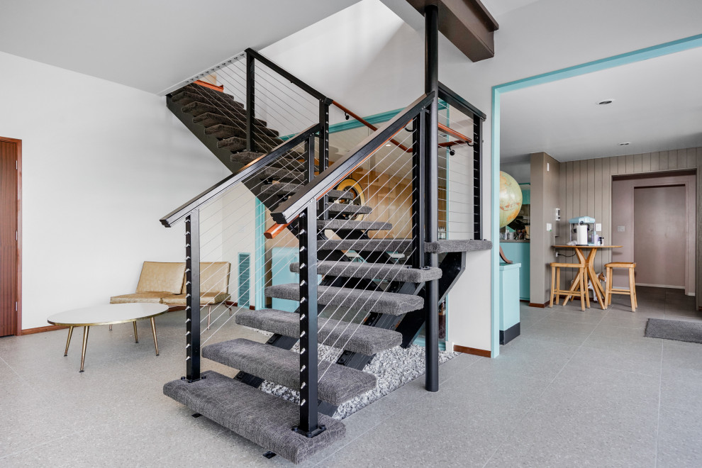This is an example of an expansive midcentury carpeted floating wire cable railing staircase in Other with open risers.