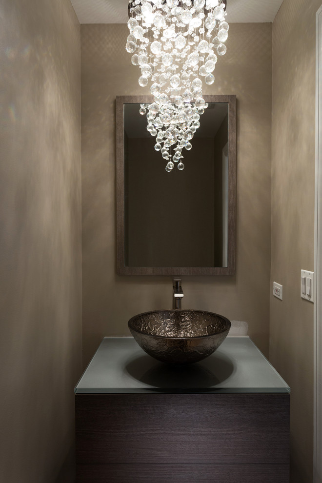 This is an example of a small modern powder room in Chicago with flat-panel cabinets, light wood cabinets, beige walls, a vessel sink, glass benchtops and grey benchtops.