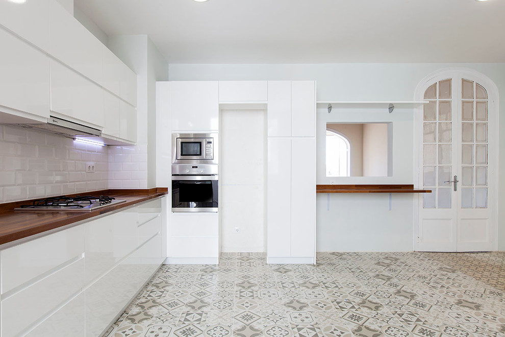 Design ideas for a large transitional single-wall open plan kitchen in Barcelona with flat-panel cabinets, white cabinets, wood benchtops, white splashback, stainless steel appliances, ceramic floors and no island.