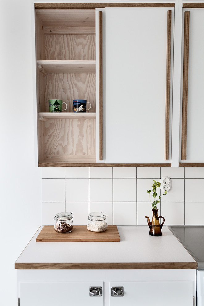 Midcentury eat-in kitchen in Malmo with a double-bowl sink, white cabinets, stainless steel benchtops, white splashback and white appliances.