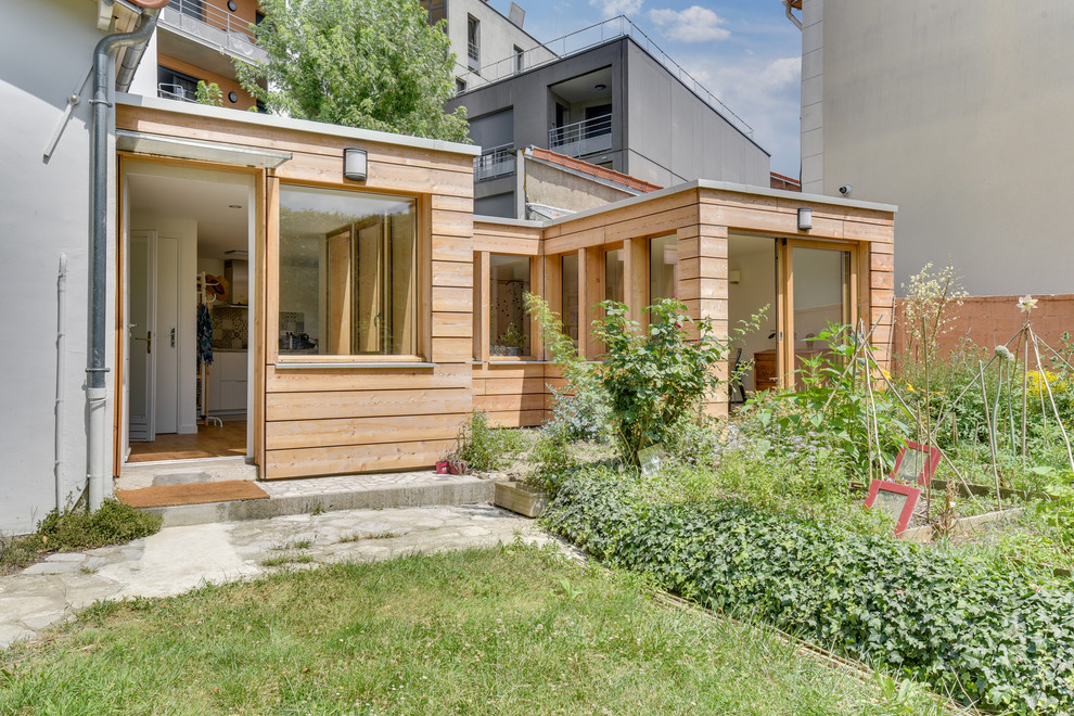 Inspiration for a mid-sized contemporary two-storey house exterior in Paris with wood siding and a flat roof.