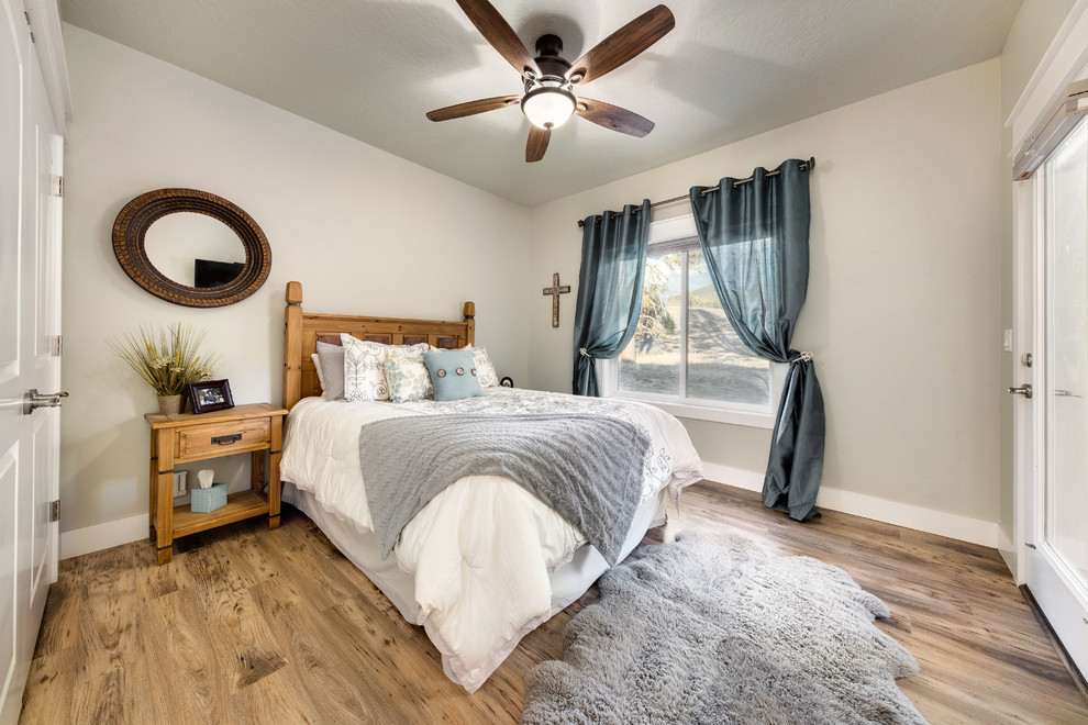 This is an example of a mid-sized country guest bedroom in Orange County with grey walls, medium hardwood floors, no fireplace and brown floor.