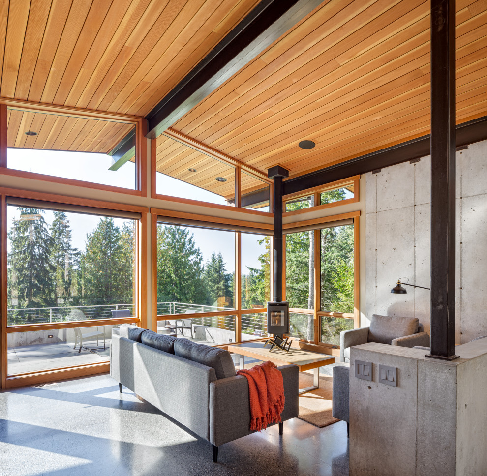 Photo of a mid-sized country enclosed living room in Seattle with concrete floors, a wood stove, no tv and vaulted.