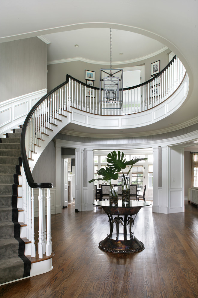 This is an example of a large transitional foyer in New York with medium hardwood floors and grey walls.