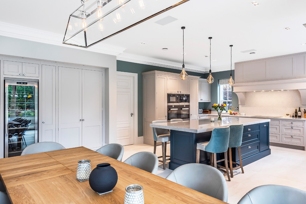 Photo of a traditional l-shaped open plan kitchen in Surrey with shaker cabinets, grey cabinets, beige splashback, with island, grey benchtop and grey floor.
