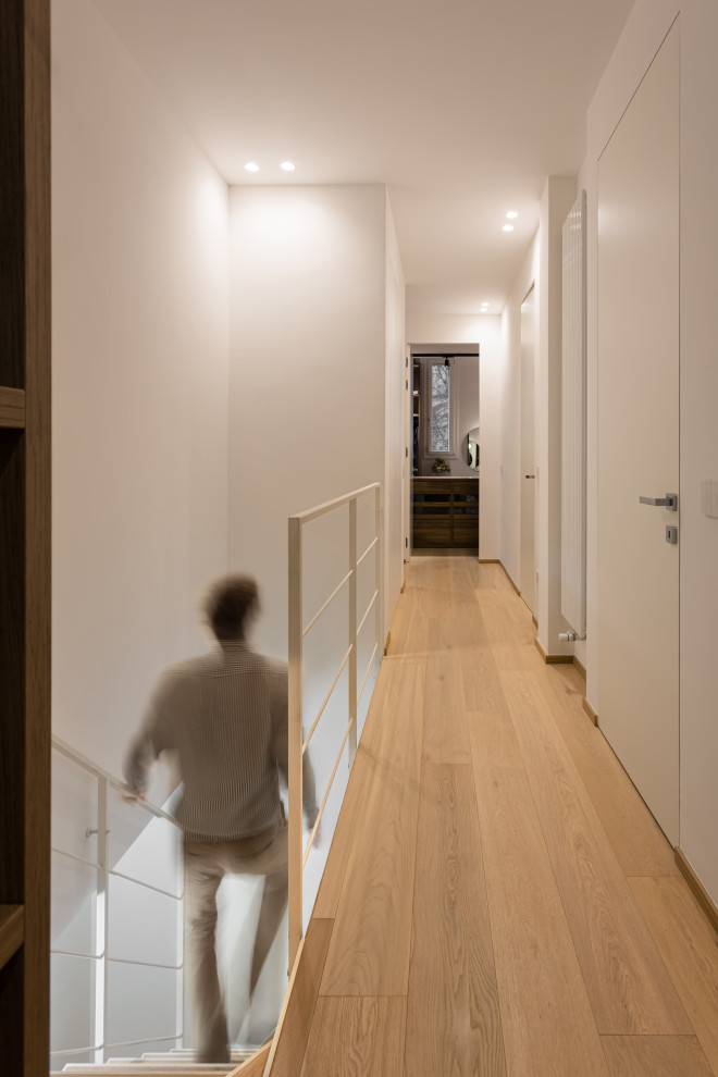 Idée de décoration pour un couloir design de taille moyenne avec un mur blanc, parquet peint et un sol beige.