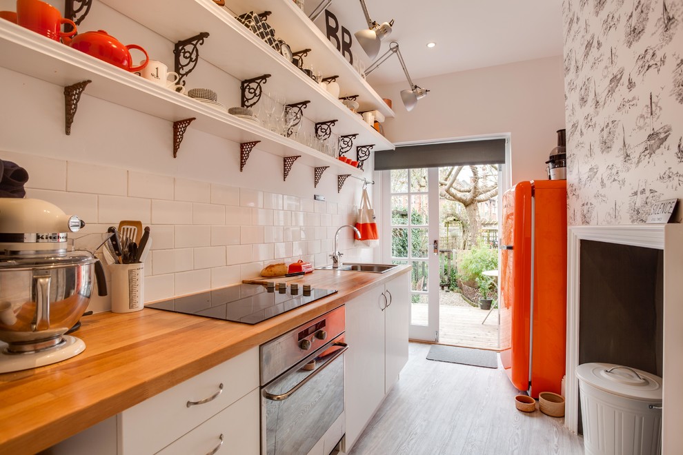 Small eclectic galley separate kitchen in Hampshire with a drop-in sink, flat-panel cabinets, white cabinets, wood benchtops, white splashback, subway tile splashback, coloured appliances, painted wood floors and no island.