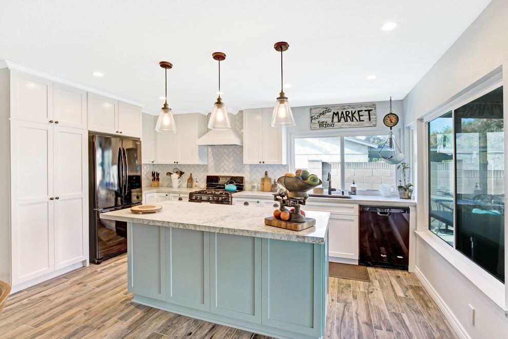 Design ideas for a mid-sized transitional l-shaped open plan kitchen in Los Angeles with an undermount sink, shaker cabinets, turquoise cabinets, marble benchtops, white splashback, marble splashback, black appliances, porcelain floors, with island, brown floor and white benchtop.