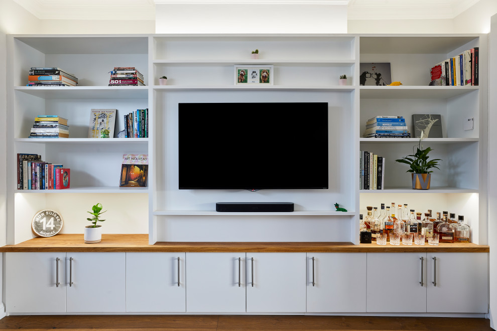 Foto di un soggiorno minimalista di medie dimensioni e aperto con pareti bianche, pavimento in legno massello medio, nessun camino, parete attrezzata e pavimento marrone