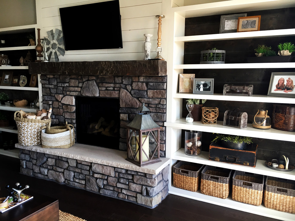 Design ideas for a country open concept family room in Other with vinyl floors, a standard fireplace, a stone fireplace surround, a wall-mounted tv and brown floor.