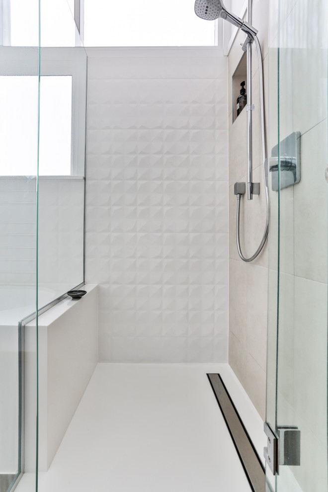 This is an example of a small modern bathroom in Auckland with furniture-like cabinets, light wood cabinets, a drop-in tub, a corner shower, white tile, ceramic tile, white walls, ceramic floors, an integrated sink, solid surface benchtops, brown floor, a hinged shower door and white benchtops.