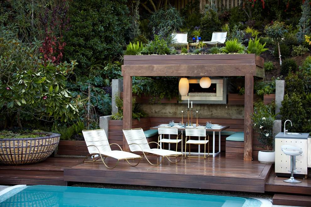 Photo of a tropical backyard deck in Los Angeles with an outdoor kitchen and a pergola.
