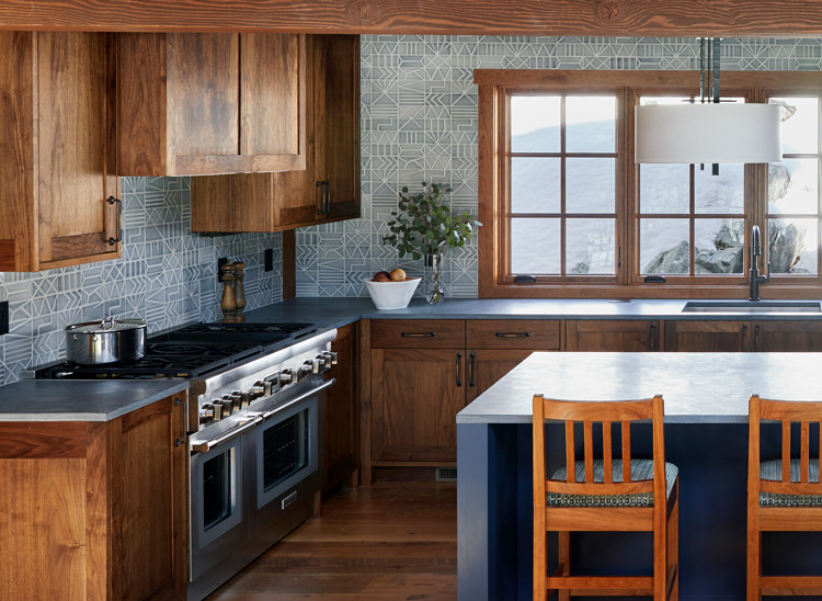 Exempel på ett mycket stort amerikanskt grå grått kök, med en enkel diskho, luckor med upphöjd panel, skåp i mellenmörkt trä, bänkskiva i täljsten, grått stänkskydd, stänkskydd i porslinskakel, rostfria vitvaror, mellanmörkt trägolv, en köksö och brunt golv
