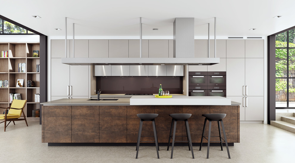This is an example of a large industrial single-wall open plan kitchen in Sydney with an undermount sink, flat-panel cabinets, beige cabinets, solid surface benchtops, brown splashback, glass sheet splashback, black appliances, concrete floors and with island.